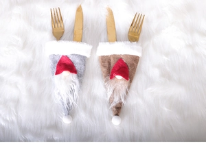 Close-up of gnome Christmas cutlery holders in grey and brown on white fur background