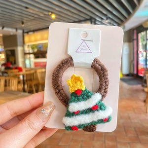 Détail d'un élastique de Noël fait main au crochet avec sapin en laine verte et rouge