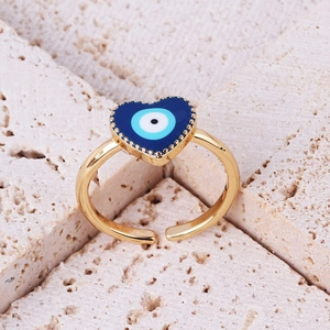 Macro shot of gold heart-shaped ring with blue enamel evil eye and textured stone
