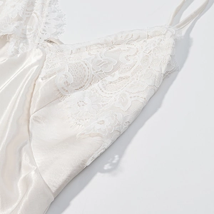 Close-up of white satin silk camisole dress featuring intricate lace trim on the neckline
