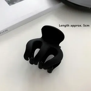Macro d'une pince à cheveux noir mat de 5cm avec mesure sur une surface blanche