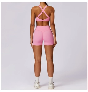 Rear view of pink high-waisted yoga shorts and cross-back sports bra on model