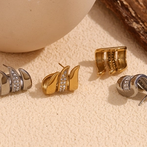 Detailed macro view of gold and silver curved claw earrings with sparkling zircon inlay