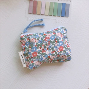 Close-up of floral cotton mini pouch with zipper detail and white label on wood