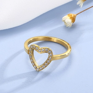 Detailed view of a gold heart-shaped ring with pavé crystals on a blue backdrop