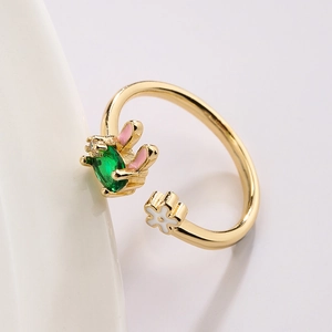 Gold plated rabbit ring with green gemstone and white flower in an open adjustable design