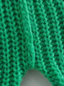 Dettaglio ravvicinato della trama a costine verde brillante di un maglione corto
