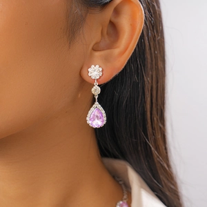 Détail de la boucle d'oreille en cristal violet avec clou floral argenté sur modèle
