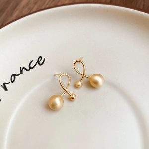 Detailed macro view of gold-plated geometric sphere earrings with matte textured finish