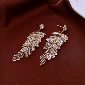 Detail view of oval cubic zirconia and crystal fringe earrings on dark brown silk fabric