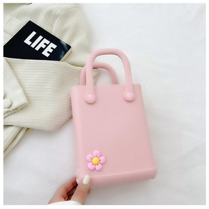 Draufsicht einer rosa EVA-Strandtasche mit süßen Blumen-Charms auf Strickhintergrund
