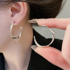 Detailed side view of silver twisted hoop earrings with a minimalist C-shape design