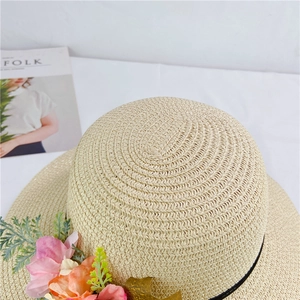 Detail of floral straw hat with colorful blossoms and woven texture on white fabric