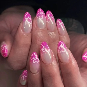 Pink gradient almond press-on nails with white heart designs and glossy finish