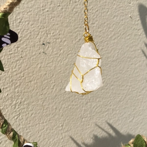 Detailed macro view of white crystal stone wrapped in golden wire on hemp rope