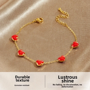 Detail of red enamel heart charms on a gold-plated stainless steel chain bracelet
