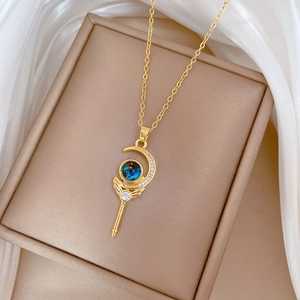 Detail of golden magic wand necklace with blue gemstone and zircons on silk background