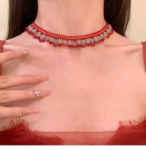 Détail macro du collier ras du cou perlé avec des breloques rouges et des motifs tressés