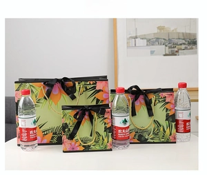 Three sizes of green floral gift bags with black silk bows and golden woven handles