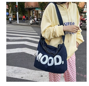 Detailed outdoor view of a large navy denim crossbody bag with white MOOD lettering