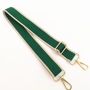 Detail of adjustable green canvas strap with beige stitching and golden metal hooks