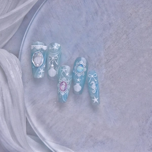 Macro view of ocean themed press-on nails with blue relief seahorse and pearl details