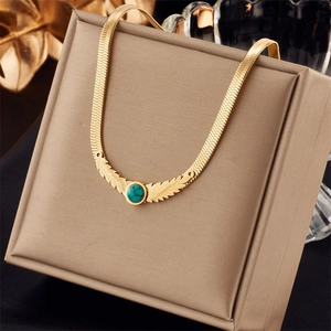 Detail of a vintage golden snake chain necklace with turquoise gem on a jewelry box