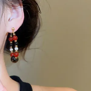 Retro circular drop earrings with tiger eye stone and pearls on a female model
