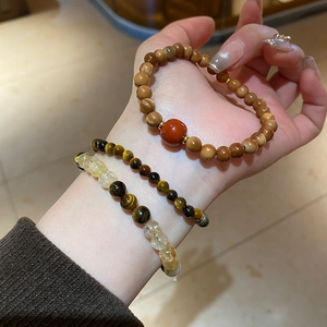 Stacked set of tiger eye and quartz beaded bracelets on wrist with warm aesthetic lighting