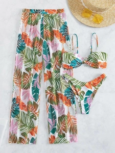 Flat lay of tropical leaf print three-piece bikini set with matching mesh beach trousers