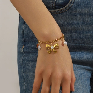 Bracelet vintage plaqué or avec breloques perle nœud et étoile sur fond en jean bleu