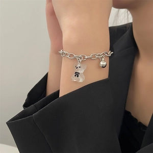 Detail eines silbernen Kettenarmbands mit transparentem Harzbär und Metallperlenanhängern