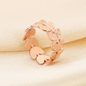 Macro shot of rose gold leaf ring on beige silk background showing refined vine texture