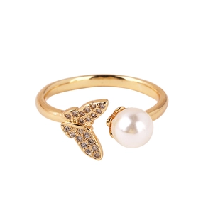 Detailed close-up of a golden butterfly ring featuring pavé zircon and a round pearl