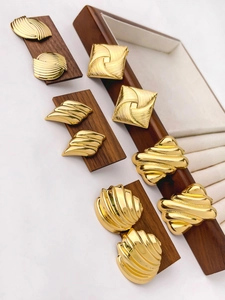 Detailed macro view of vintage geometric gold alloy earrings with various textures on wood
