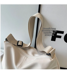 Detail of adjustable wide shoulder strap and metal zipper on cream nylon tote bag
