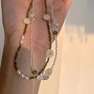 Detailed close-up of handmade beaded necklace with green zircon daisies and freshwater pearls