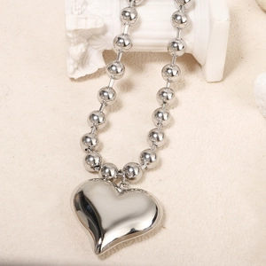 Macro view of polished silver heart pendant on a beaded ball chain necklace