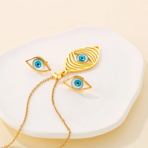Detail of bohemian evil eye jewelry set with gold necklace and earrings on white plate