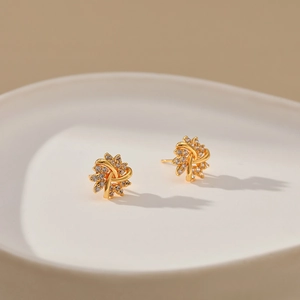 Macro shot of gold-plated flower stud earrings with shimmering zircon petals