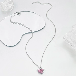 Collar de planeta corazón rosa con cadena de plata y detalle de anillo Saturno sobre espejo