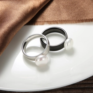 Close-up of pearl rings in silver and black on a satin fabric and ceramic tray