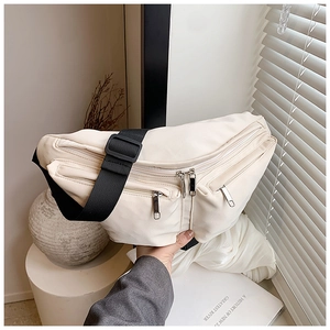 Detail of off-white crossbody chest bag with silver zippers and black nylon strap