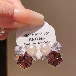 Macro shot of Silver 925 bow earrings with white pearl and large purple crystal pendant