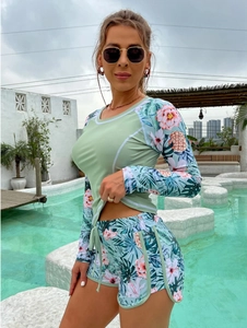 Detail of light green long-sleeve surf swimsuit set with tropical floral print on shorts