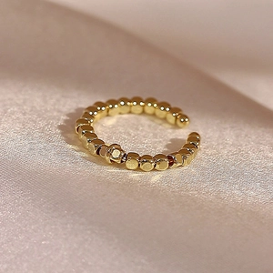 Macro dettagliata dell'anello con perline placcato oro 14k su tessuto di seta champagne