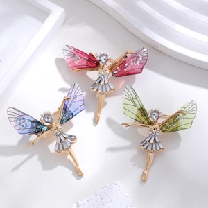 Three elegant ballet fairy brooches with sparkling crystals and colorful wings on marble