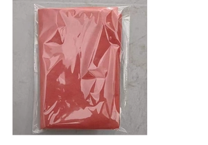 Folded red non-woven Christmas chair cover packed in clear plastic bag on a grey surface