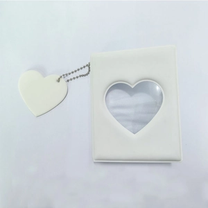 Close-up of a white photocard album with a heart-shaped cutout and matching charm