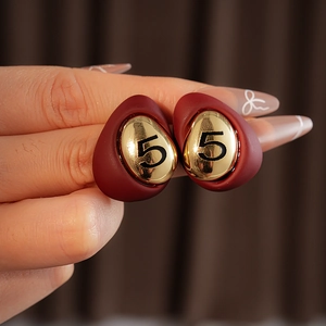 Detail of red enamel waterdrop earring with gold number 5 engraving in close-up
